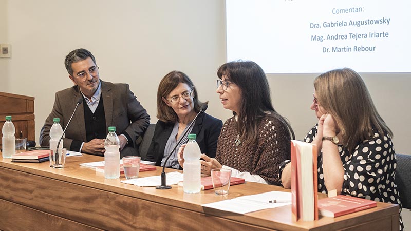 Verónica Calcagno durante su exposición, hablando en una mesa, en la que también se ve a Martín Rebour, Gabriela Augustowsky y Andrea Tejera Iriarte, comentaristas del evento