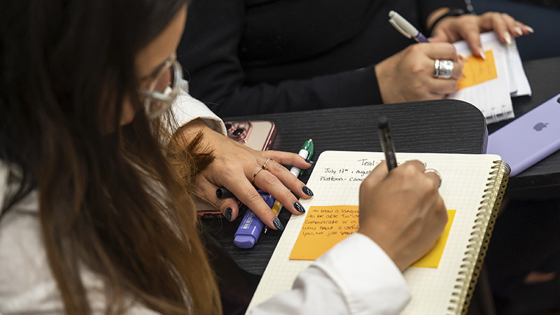 Manos de una profesora escribiendo en un cuaderno